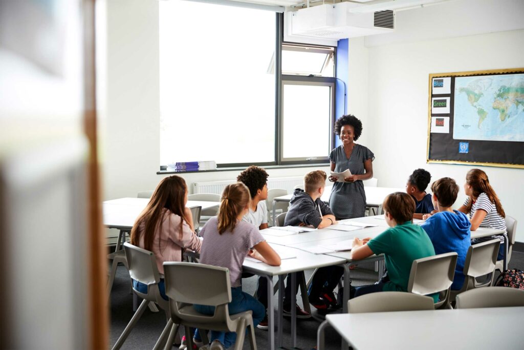 Female High School Teacher Standing by Table in Classroom